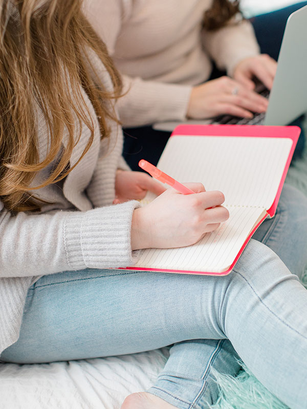 Something Blue Studio - Marketing and Design for Creative Entrepreneurs - Hannah writing in notebook on bed in jeans-updated